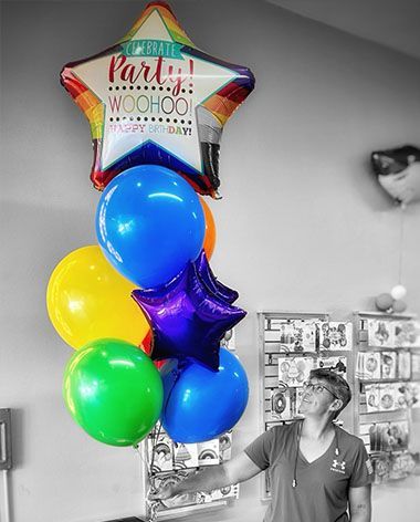 A woman is holding a bunch of balloons in a room.