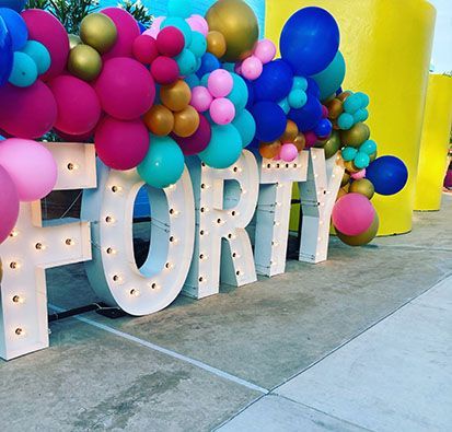 The word forty is surrounded by balloons and lights