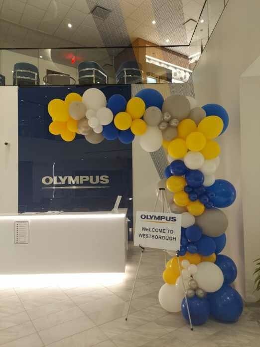 Blue and yellow balloons in front of a sign that says olympus