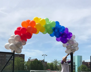 A man is holding a bunch of balloons in the shape of a rainbow