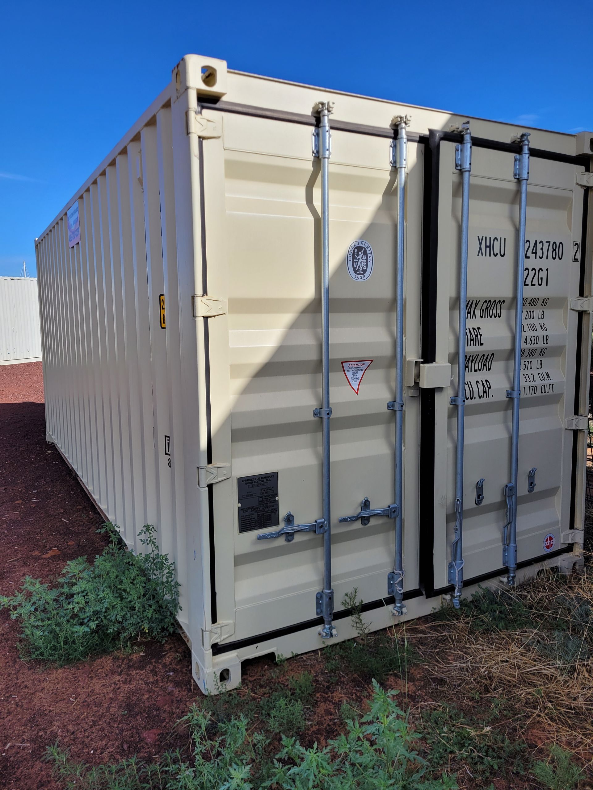 A large white shipping container is sitting on top of a dirt field.