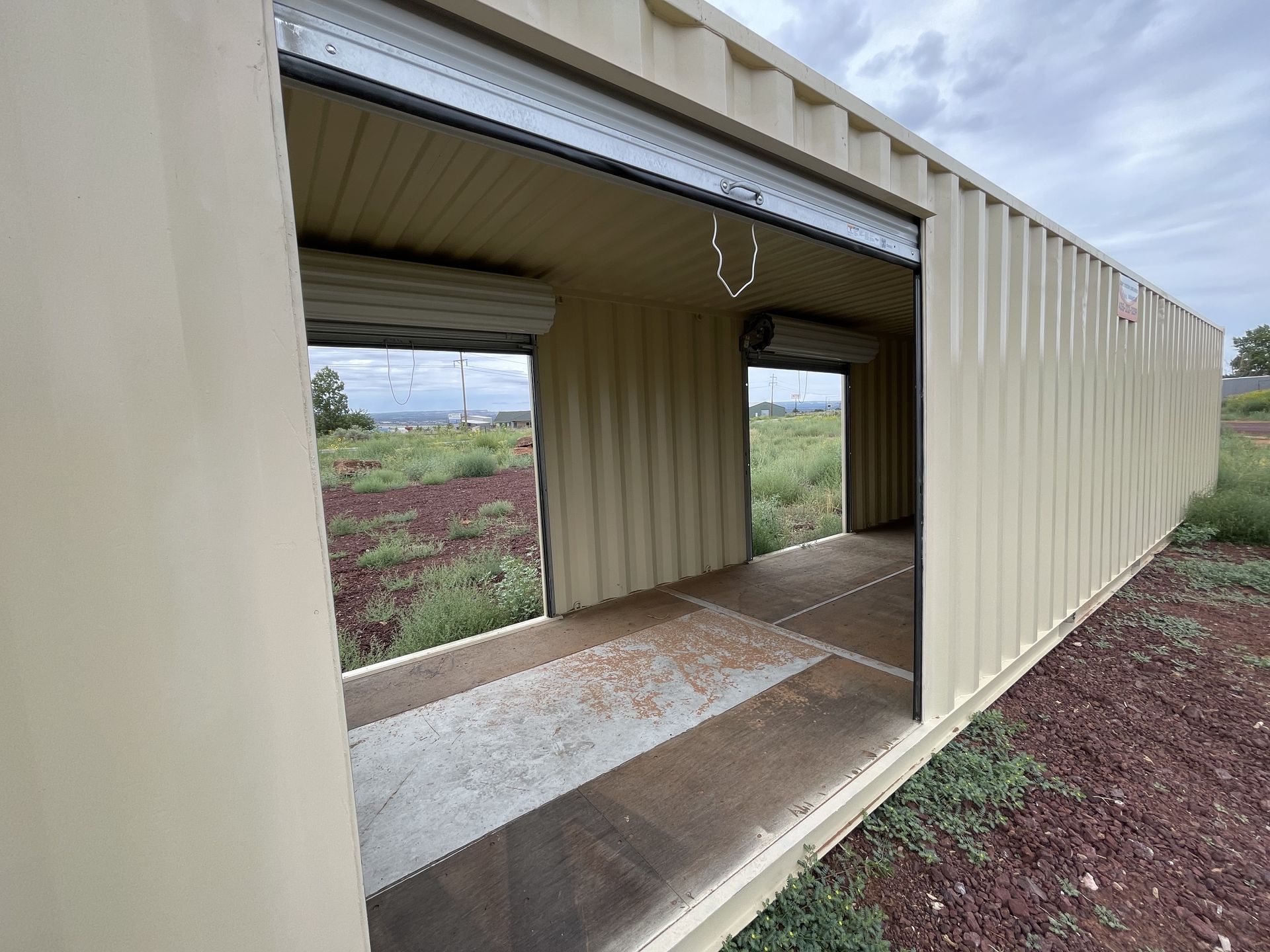 A shipping container with the door open and a roll up door.
