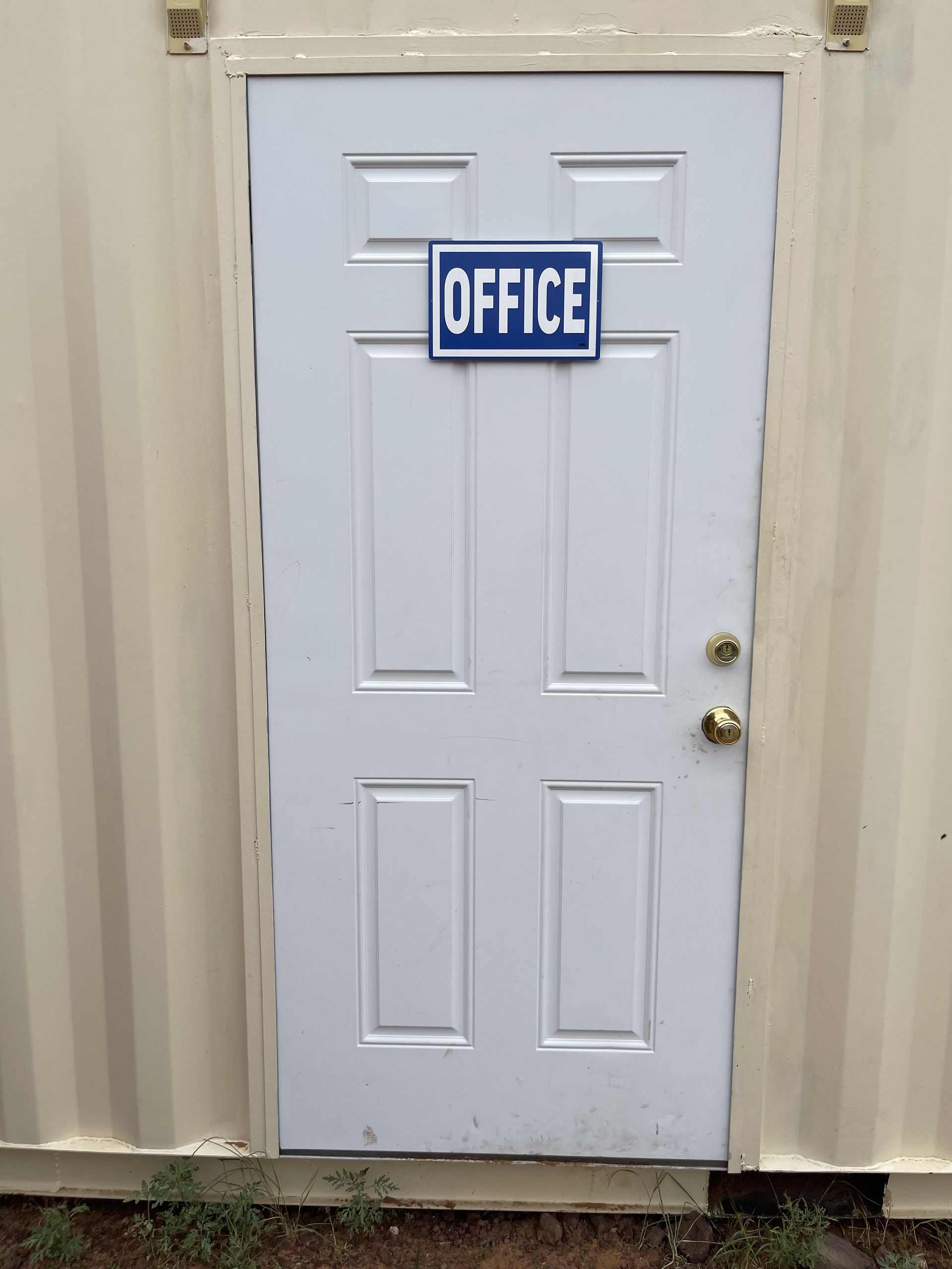 A white door with a blue sign that says office
