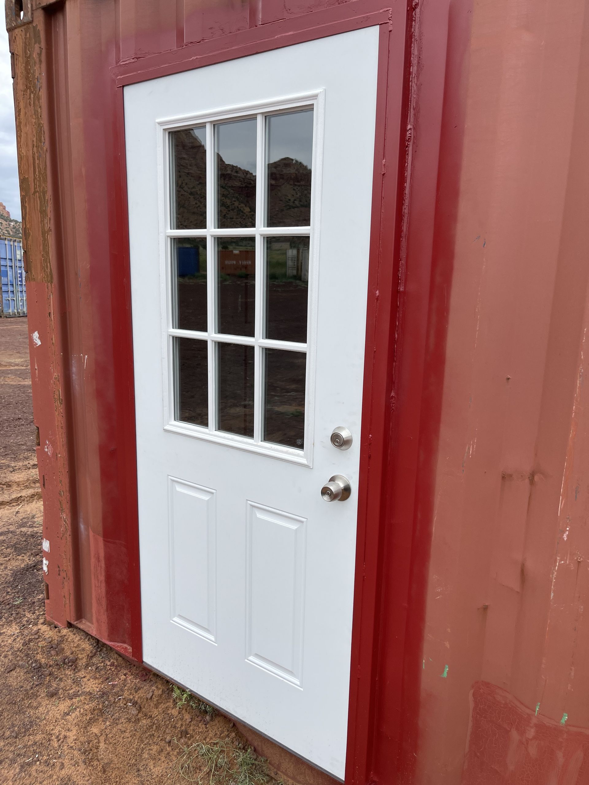 A red building with a white door and a window.