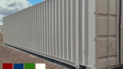 A large white shipping container is sitting on top of a dirt field.