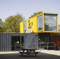 A yellow shipping container has the word glass on it