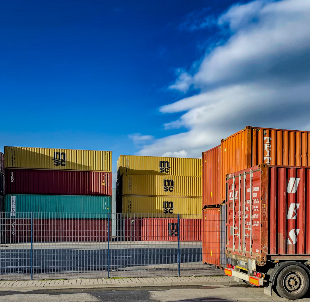 A truck is parked in front of a row of shipping containers.
