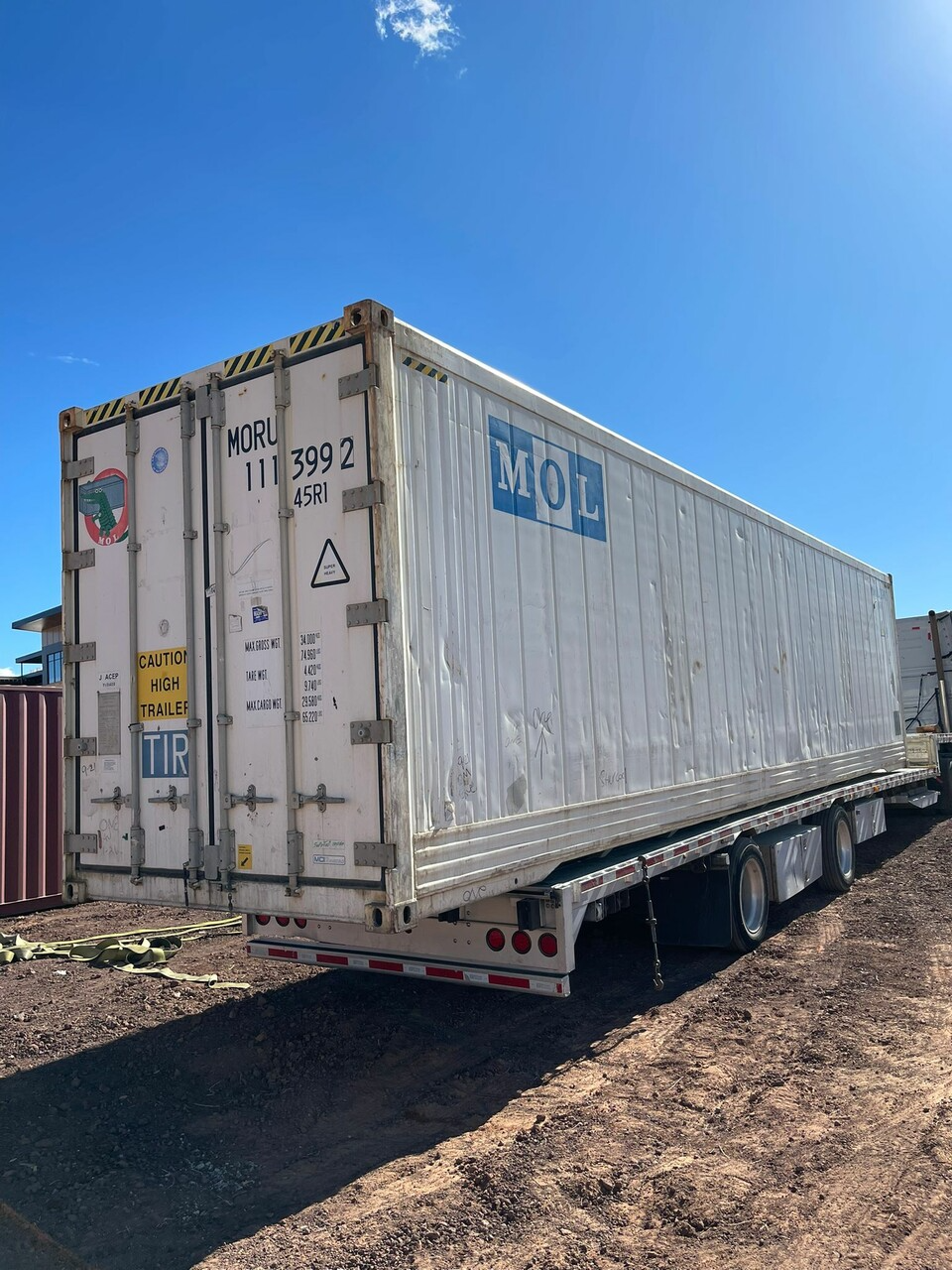 A white mol trailer is parked in the dirt