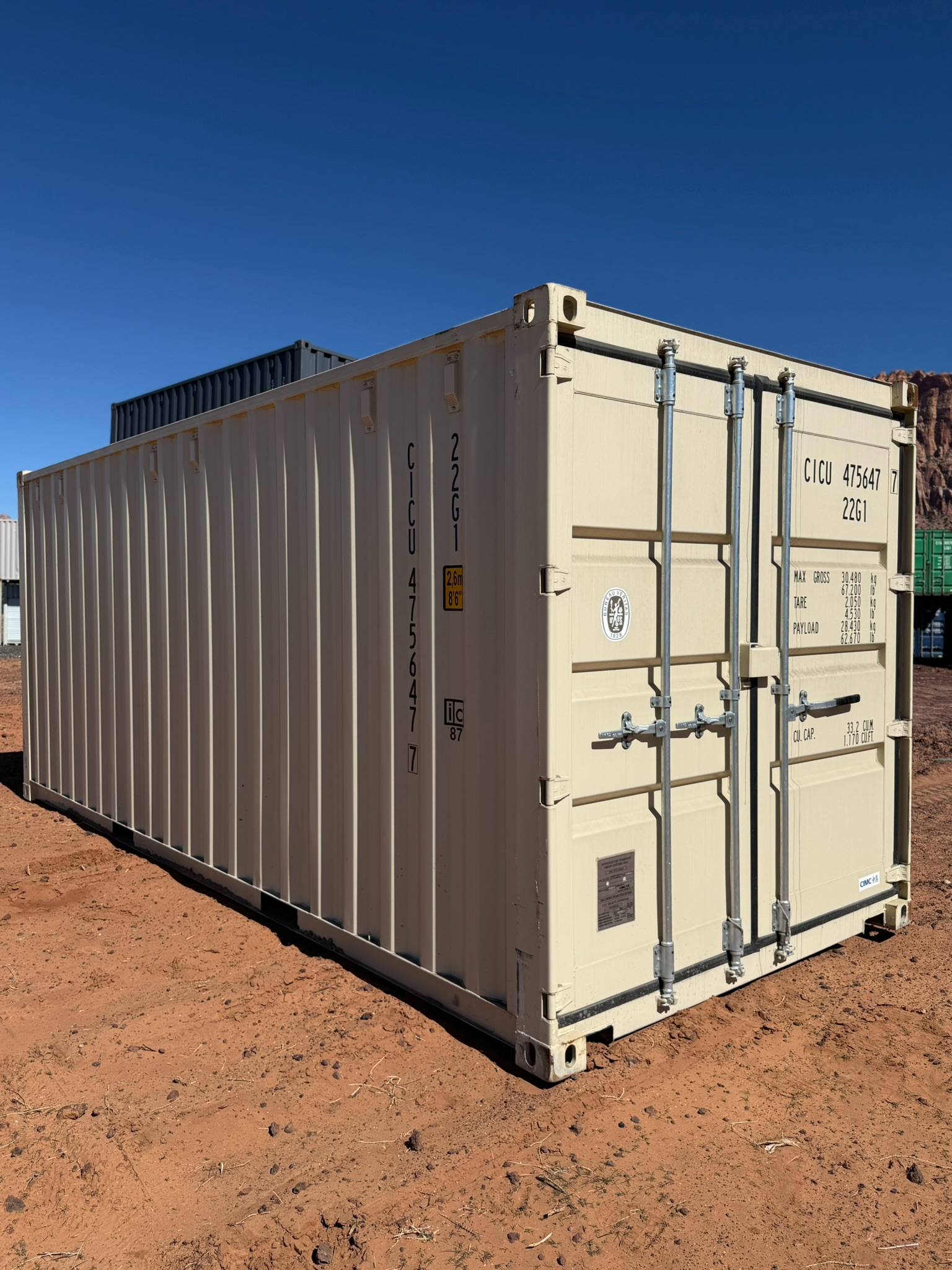 A shipping container is sitting on top of a dirt field.