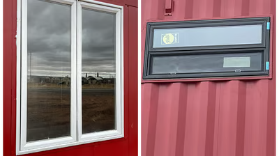 A red shipping container with a white window and a black window.