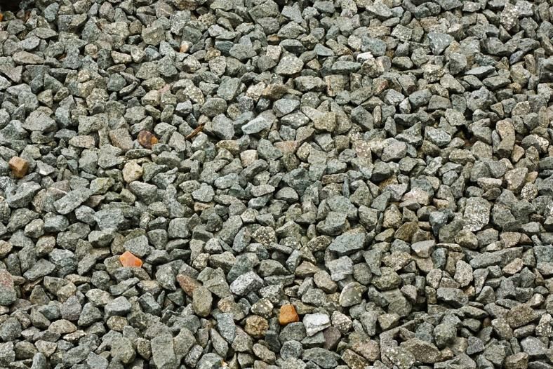Gravel rock pile, various shades of gray and tan, scattered texture.