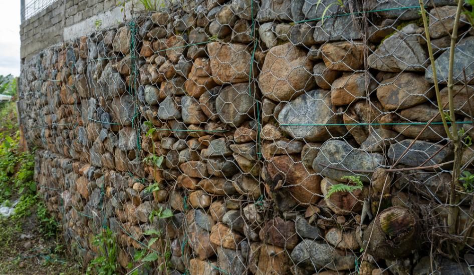 A Stone Wall with A Chain Link Fence Surrounding It — S & L Sand & Gravel in Byron Bay, NSW