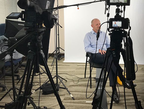 Interview setup with cameras filming a seated speaker against a white backdrop