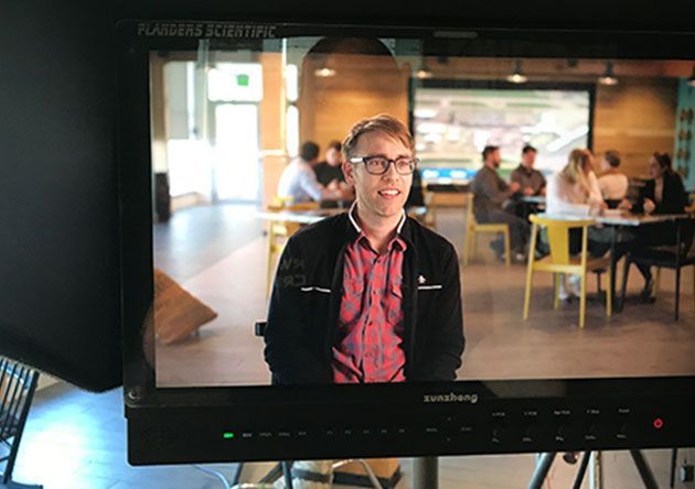 Man in glasses and red shirt seated in a restaurant, seen on a monitor