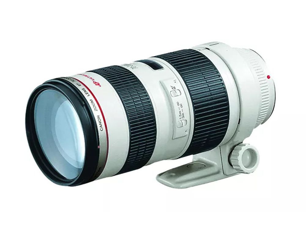 White telephoto camera lens with black rings and tripod mount on a white background