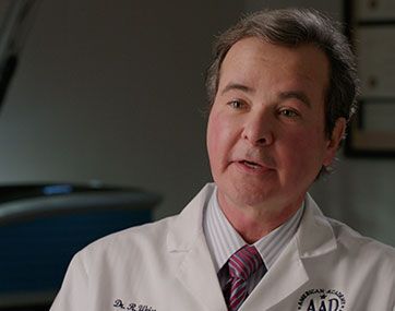 Doctor in white coat and tie speaking in an office setting