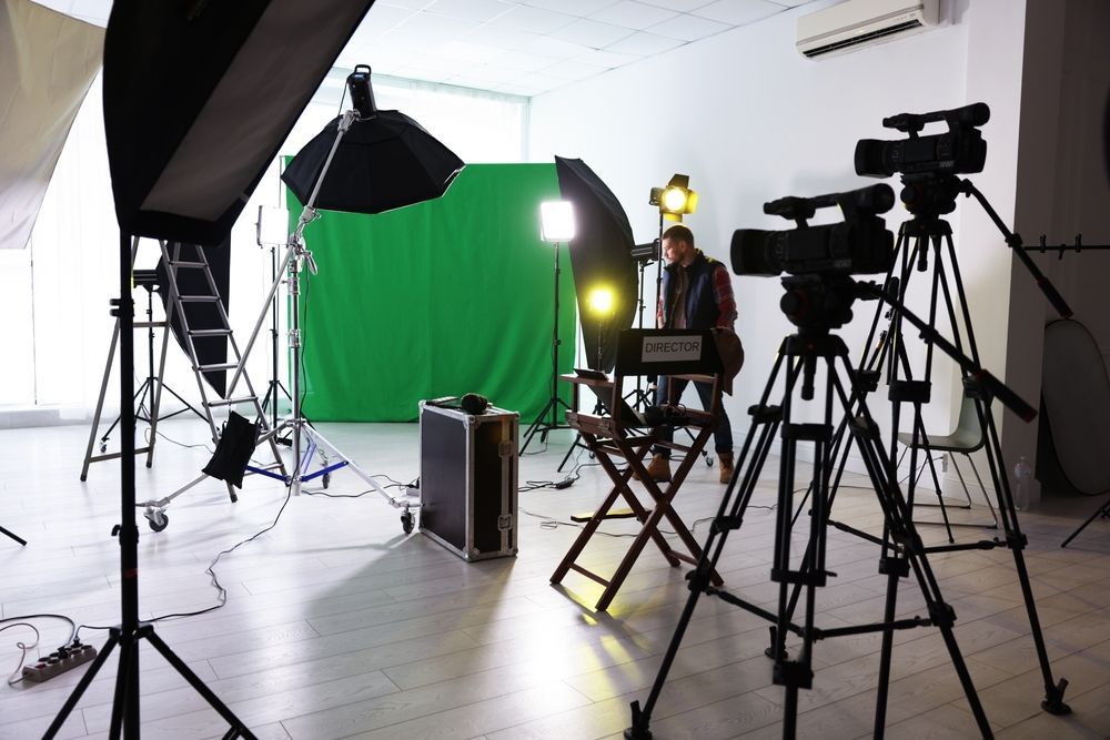 Photo studio with green screen, lighting gear, and multiple cameras on tripods