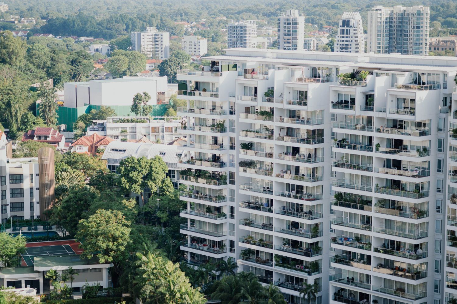 An aerial view of a white, multi-story modern residential apartment complex.