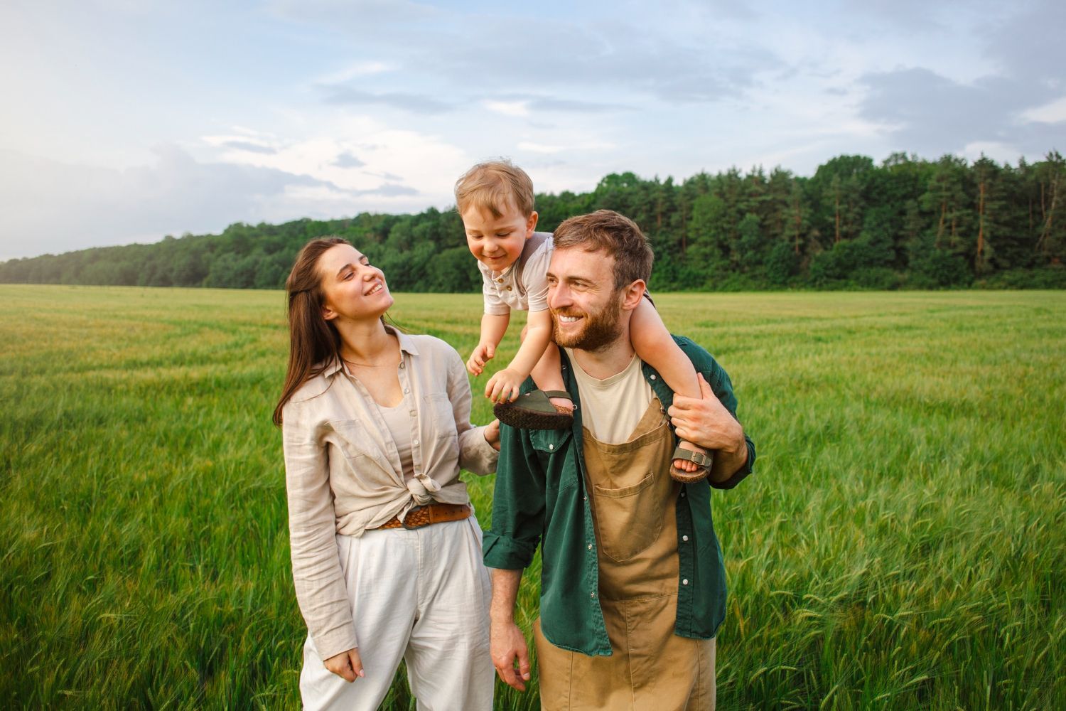 Couple reviewing paperwork with a professional in a home. The woman embraces the man while the other woman holds documents.