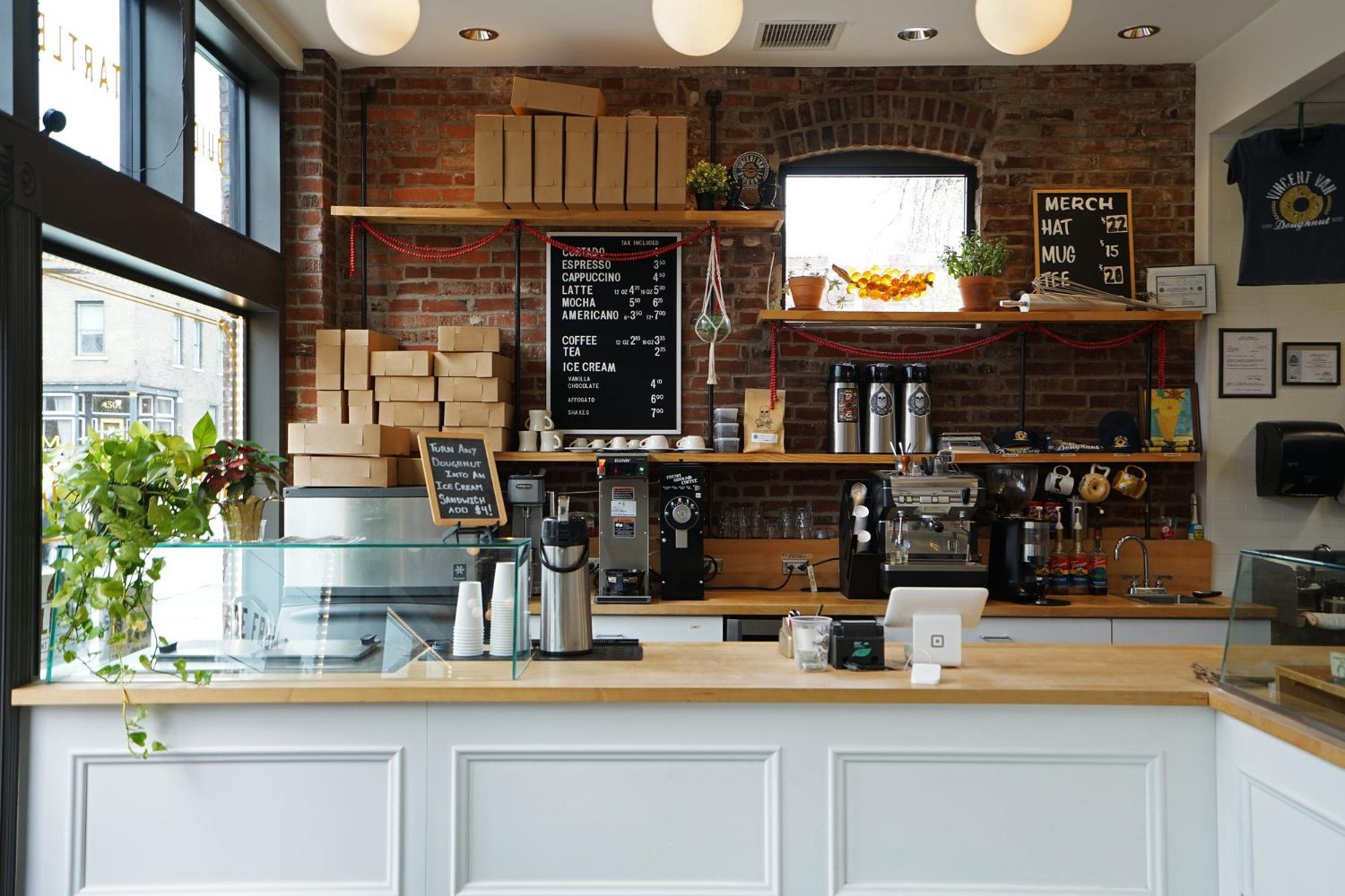 Couple in a convertible car, smiling while driving through a green, wooded area on a sunny day.