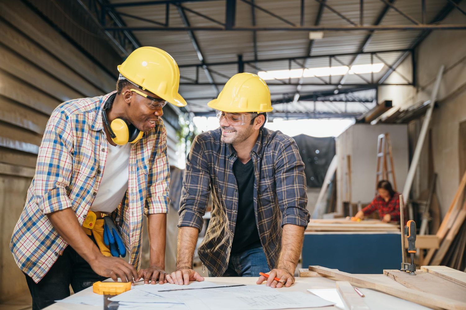 Three people, including two in hard hats and vests, looking at a clipboard outdoors.