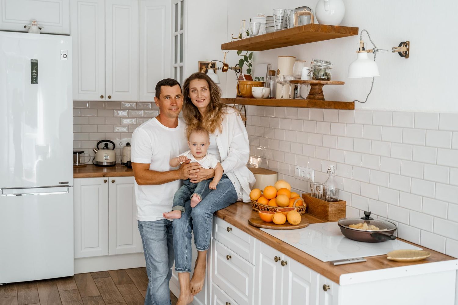 Couple in a convertible car, smiling while driving through a green, wooded area on a sunny day.