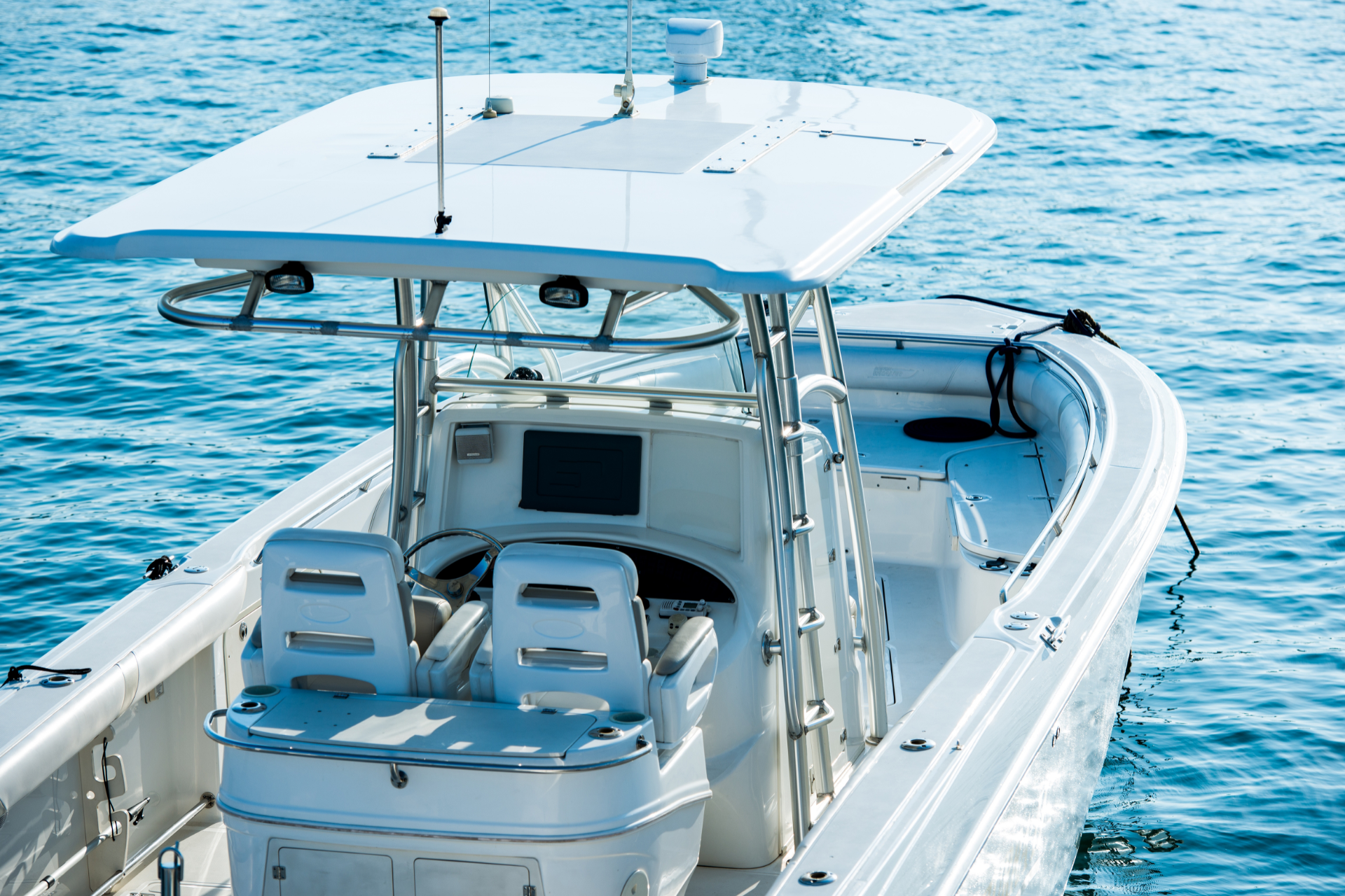 A white center console boat with a T-top canopy floating on calm blue water.