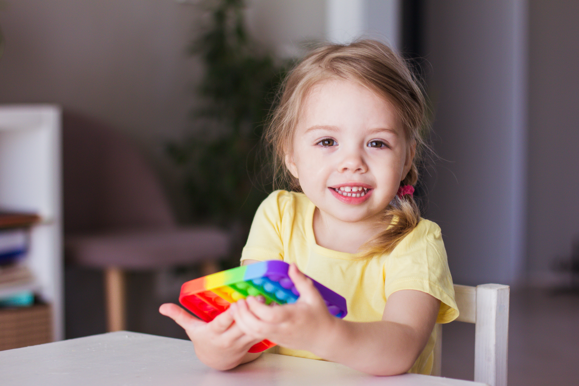 Couple in a convertible car, smiling while driving through a green, wooded area on a sunny day.