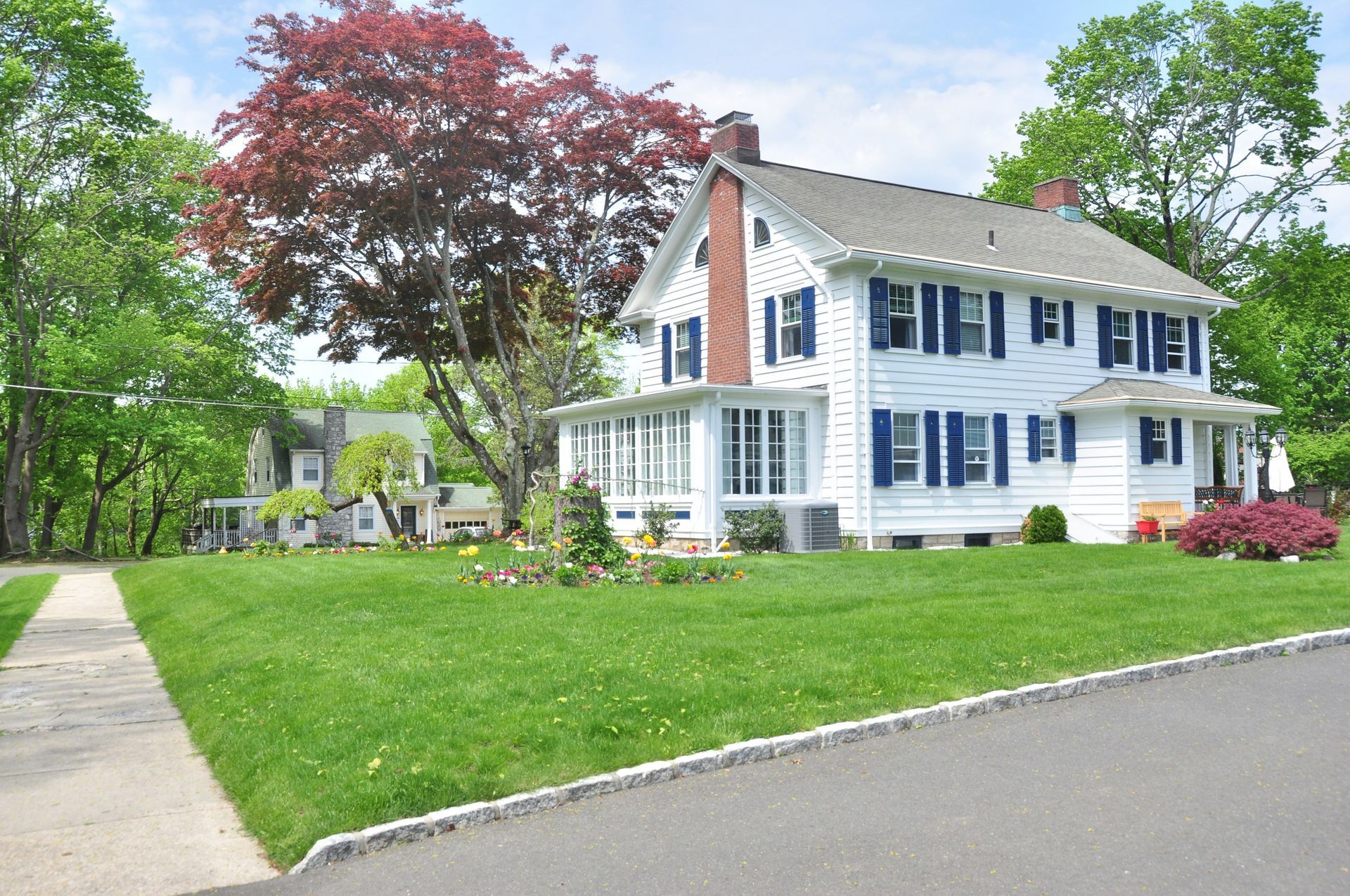A family is sitting on the porch of their house next to a swimming pool.