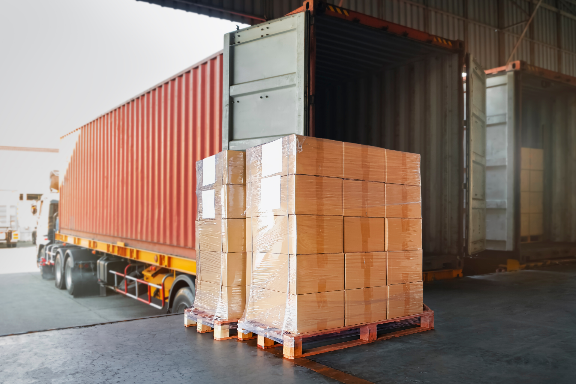 Couple in a convertible car, smiling while driving through a green, wooded area on a sunny day.