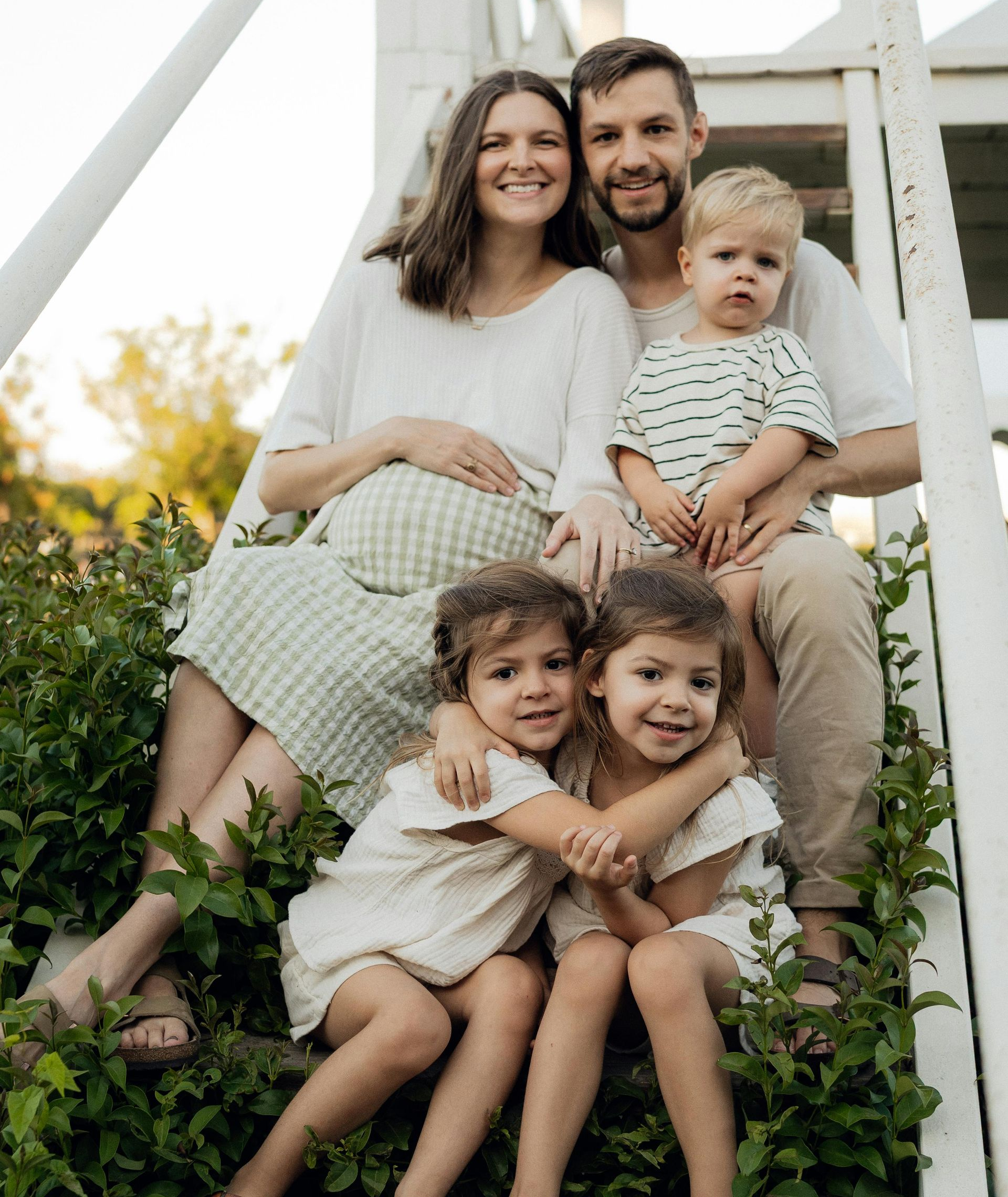 A family is sitting on the porch of their house next to a swimming pool.