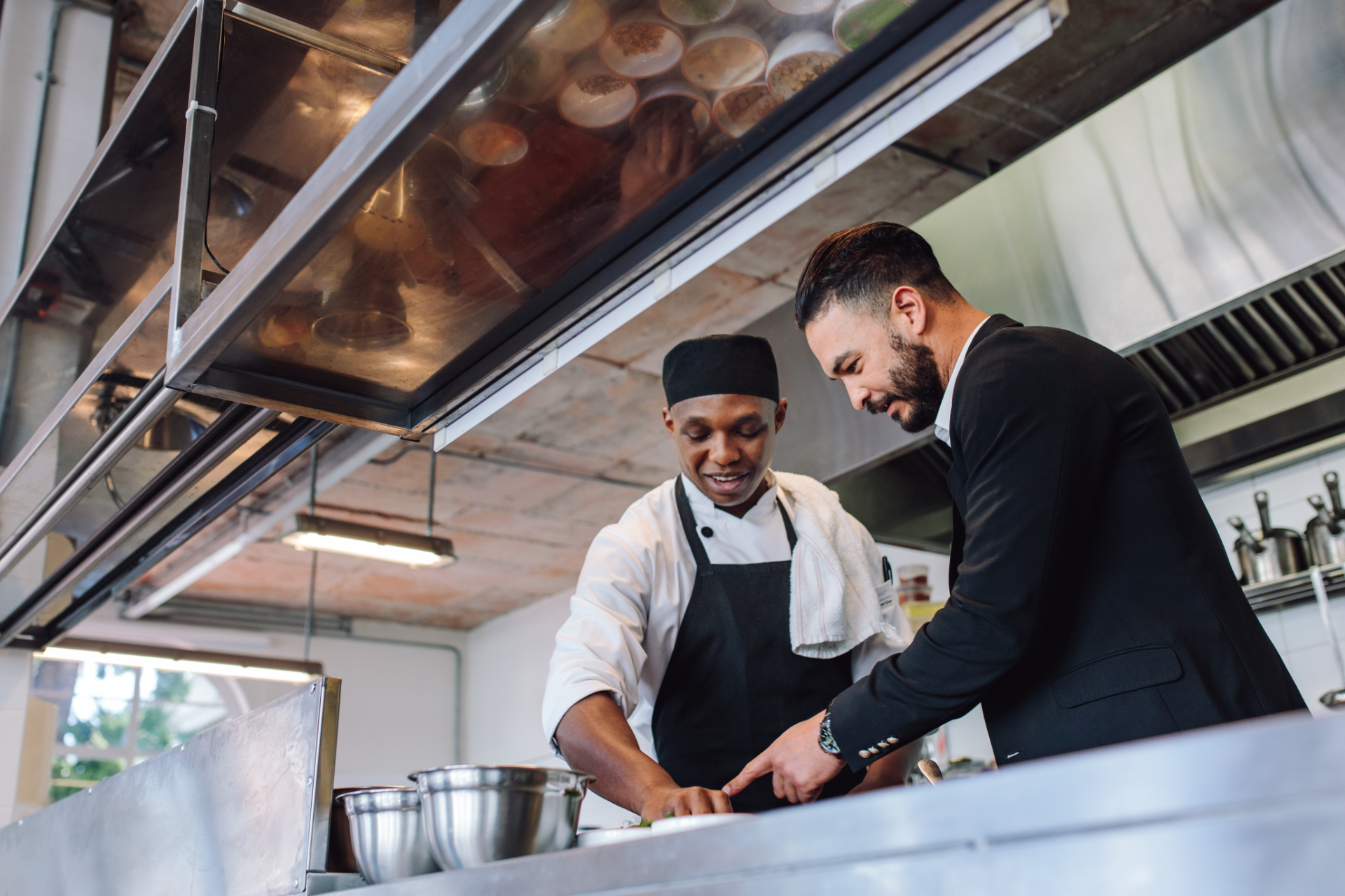 Couple in a convertible car, smiling while driving through a green, wooded area on a sunny day.