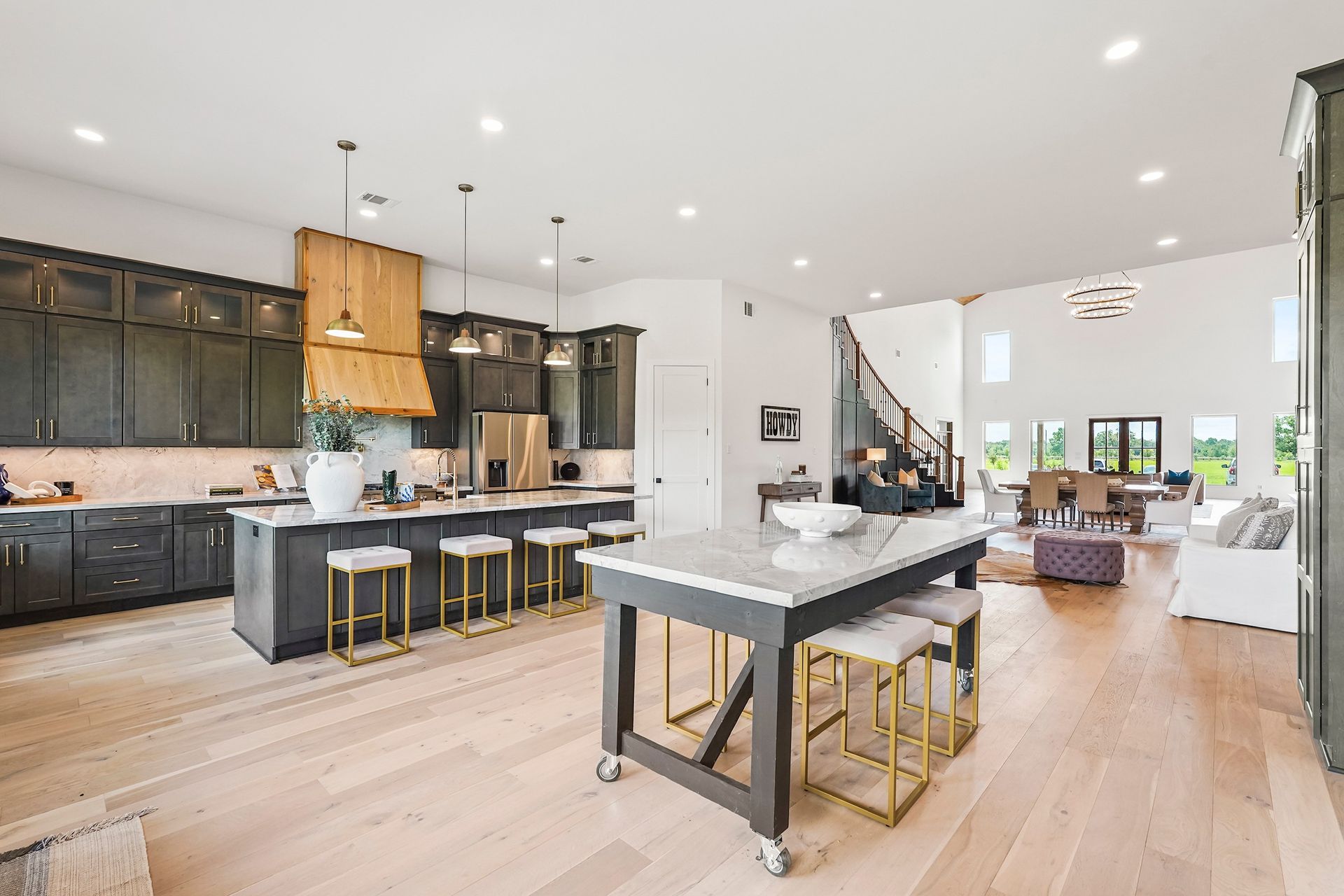 Open-concept kitchen with dark cabinets, large island with stools, and light wood floors.