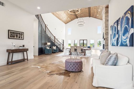 Spacious living room with wood floors, a staircase, and a dining area, featuring a cowhide rug and artwork. Spacious living room with wood floors, a staircase, and a dining area, featuring a cowhide rug and artwork.