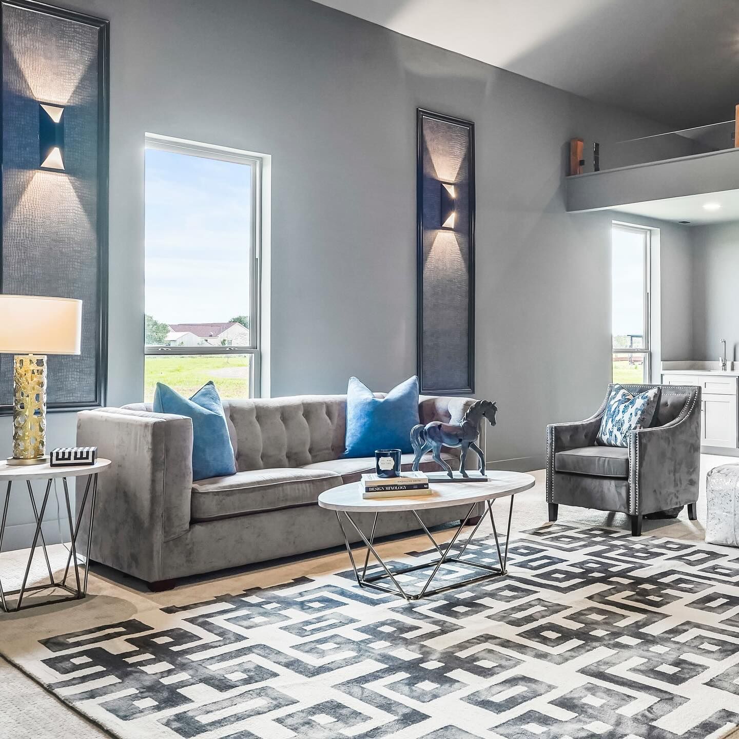 Gray living room with sofa, chair, rug, and modern wall sconces.
