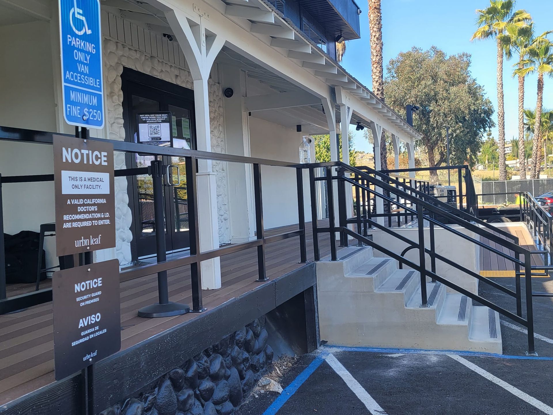 A handicapped parking sign is on the side of a building next to a ramp.