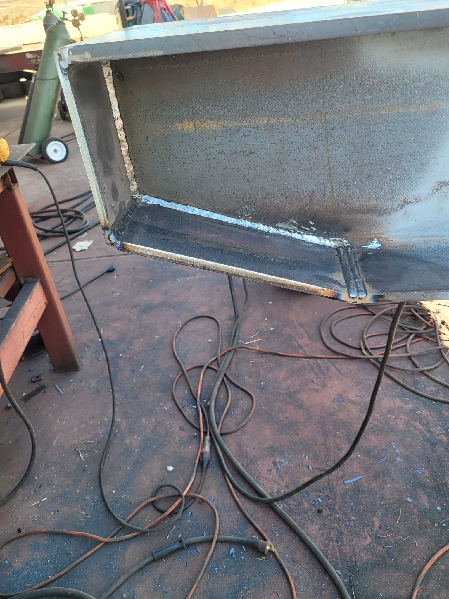 A piece of metal is being welding on the ground.