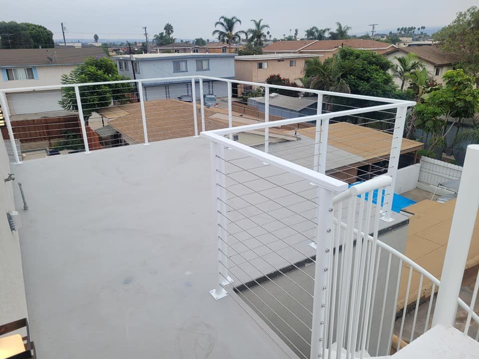 A rooftop deck with a white railing and stairs