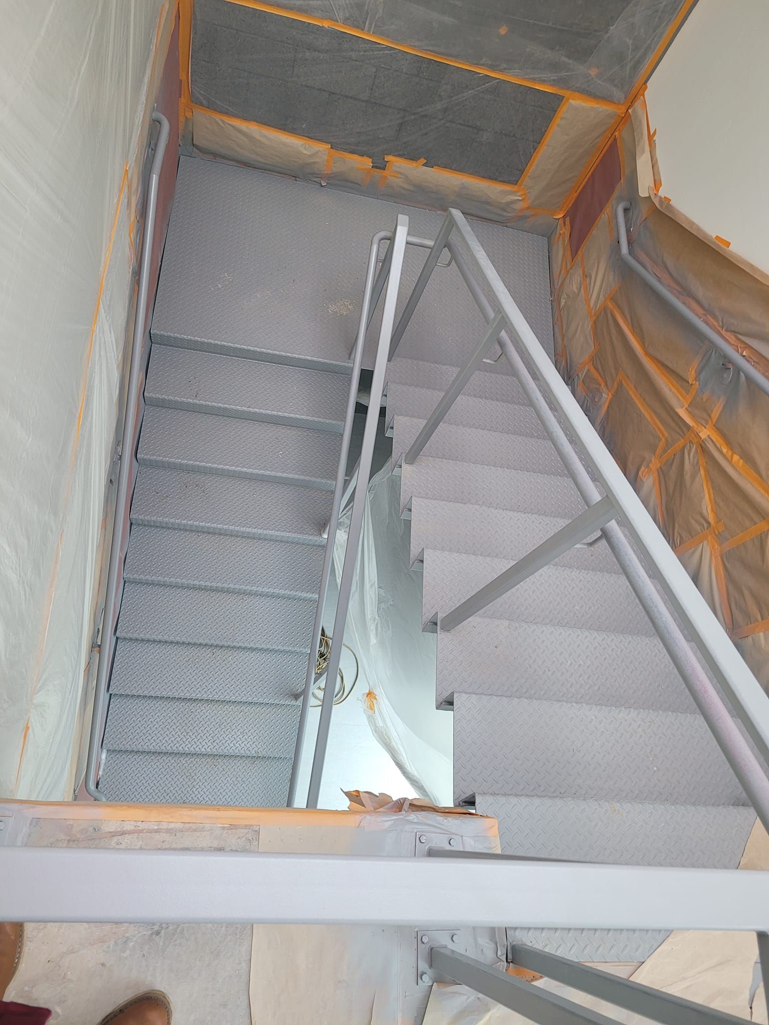 A person is standing on the bottom of a staircase.