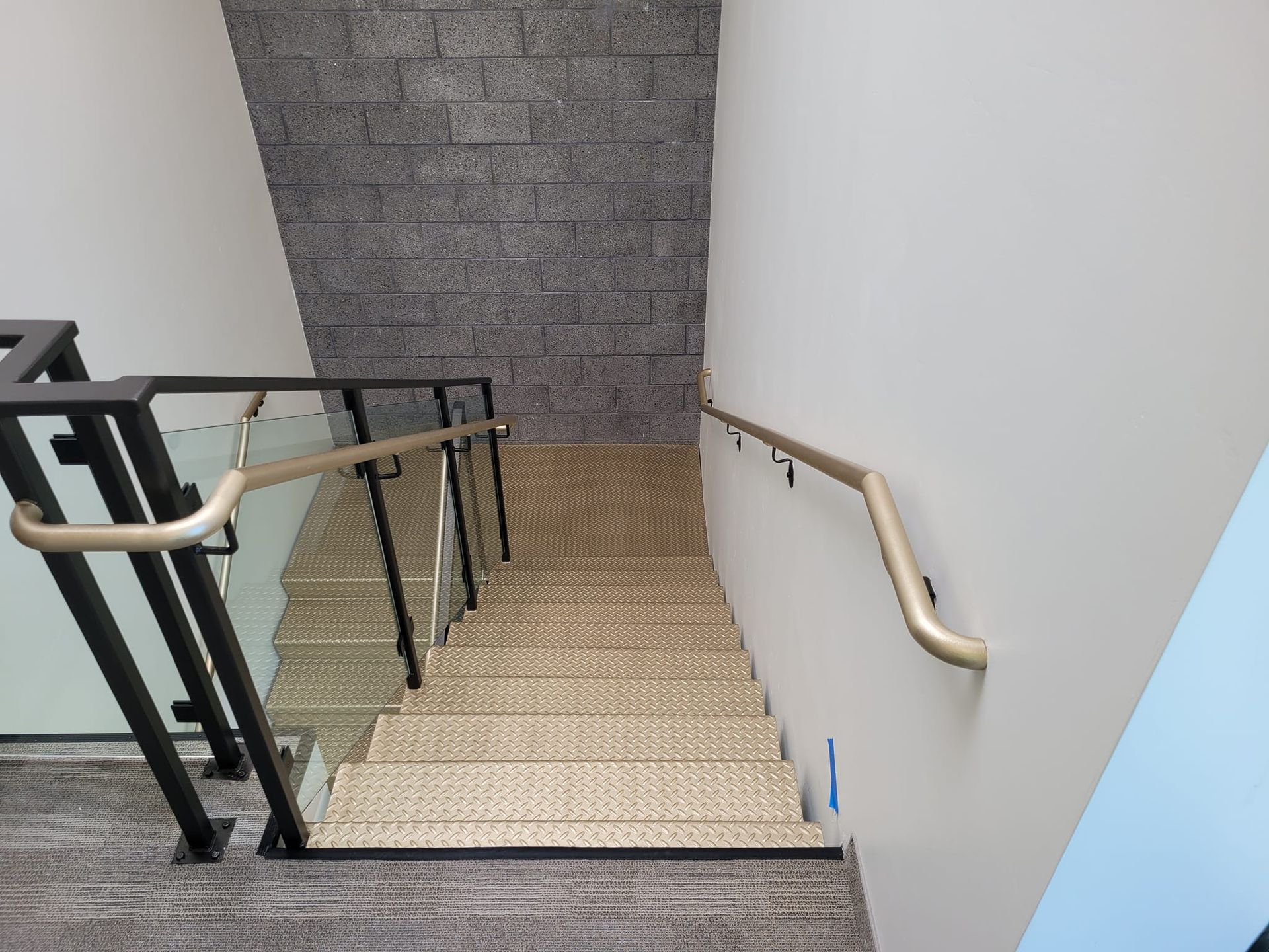 A staircase with a glass railing and a brick wall.