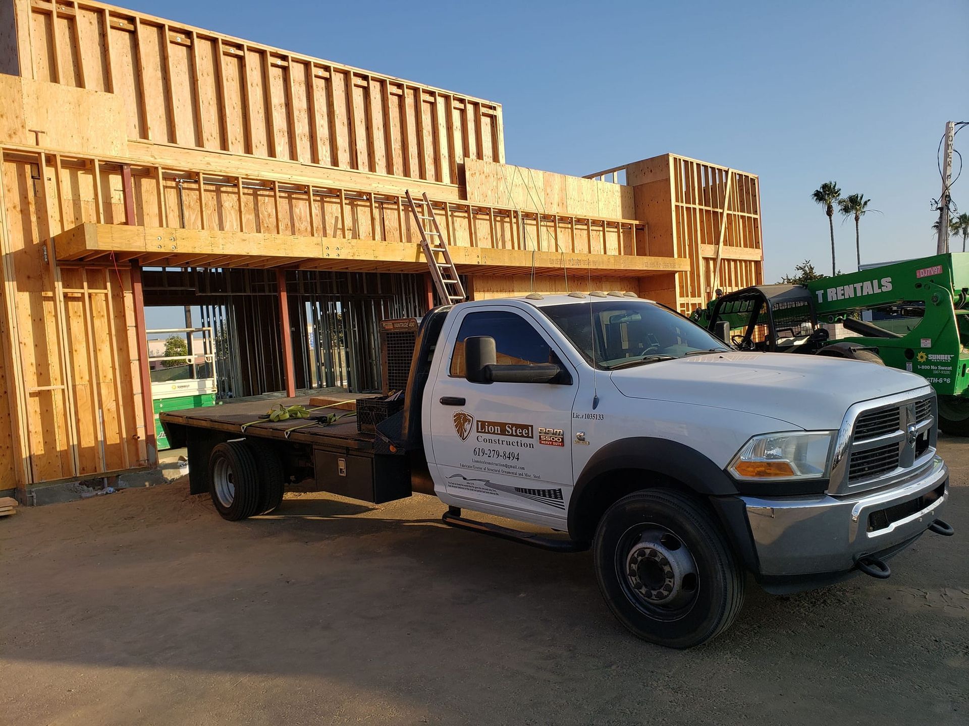 A white truck is parked in front of a building under construction.