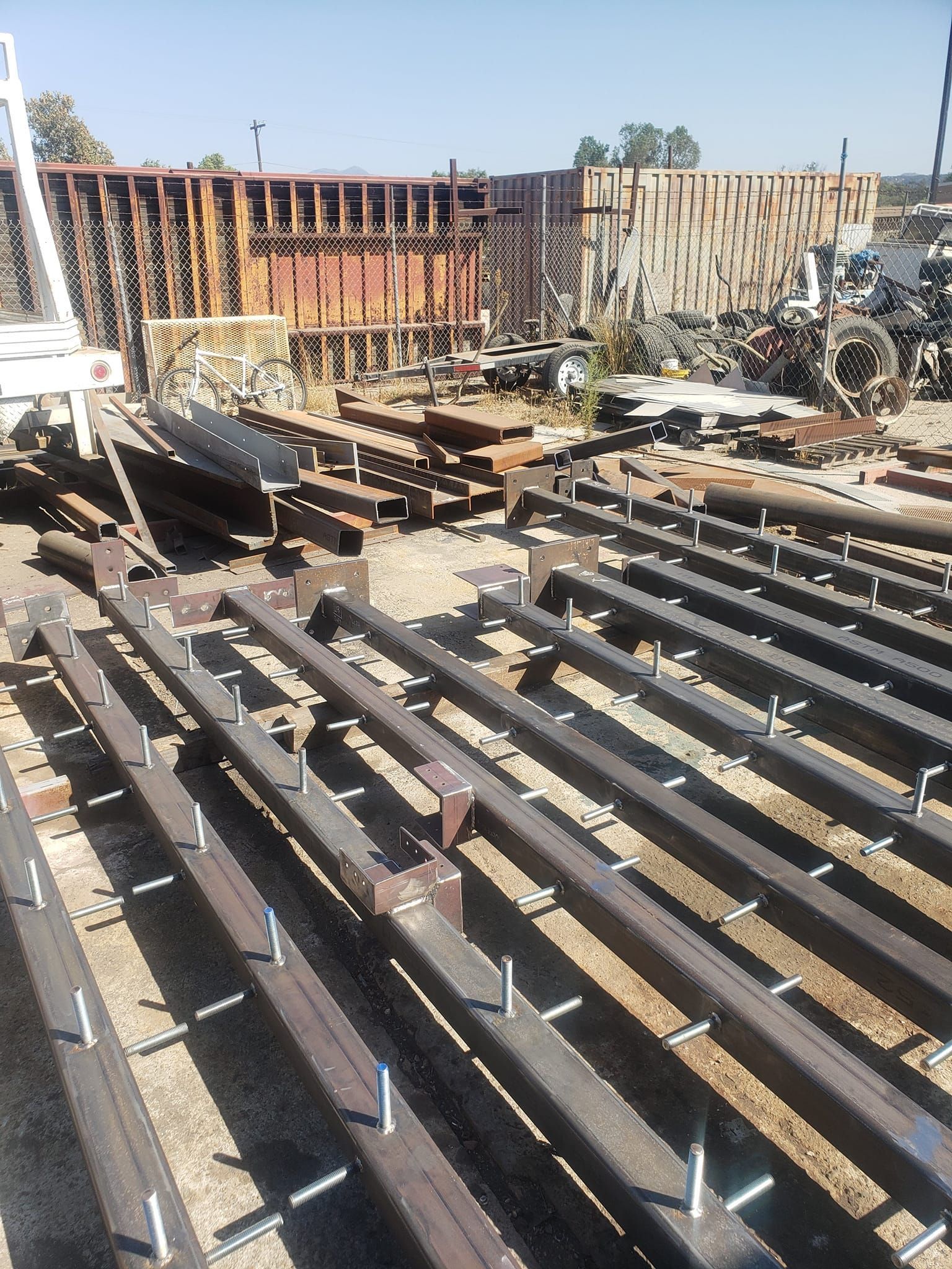 A bunch of metal beams are sitting on the ground in a yard.