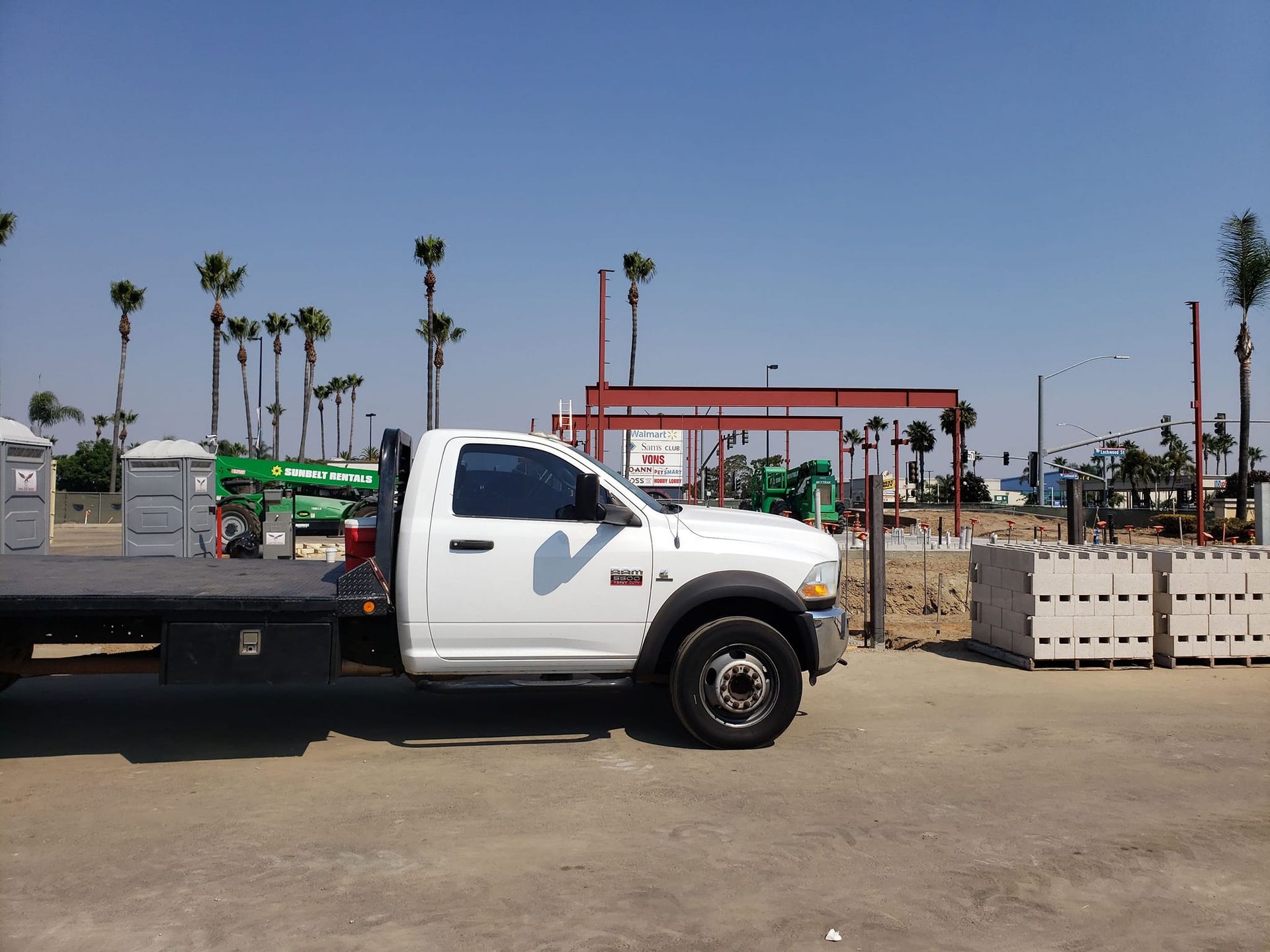 A white flatbed truck is parked in a parking lot