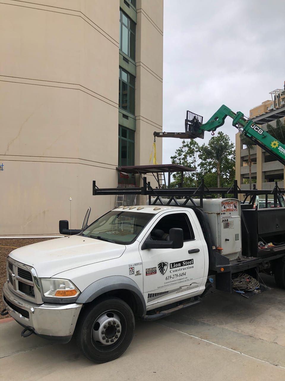 A white truck with a crane on the back is parked in front of a building.