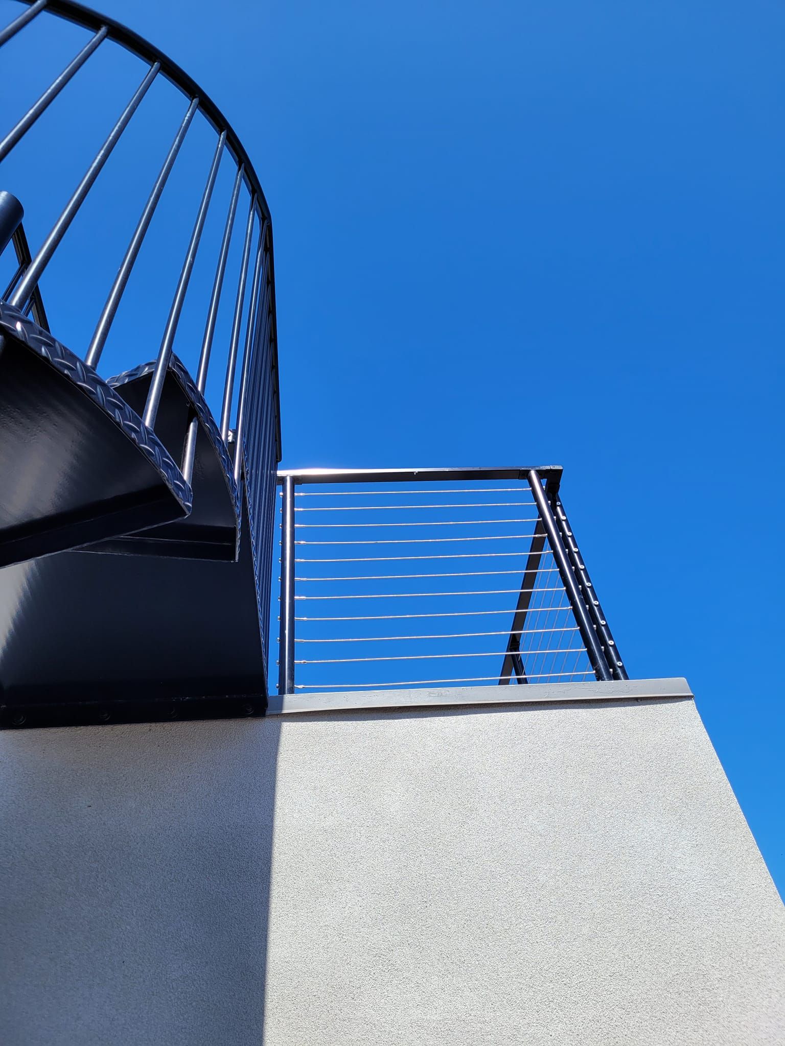 Looking up at a spiral staircase with a blue sky in the background
