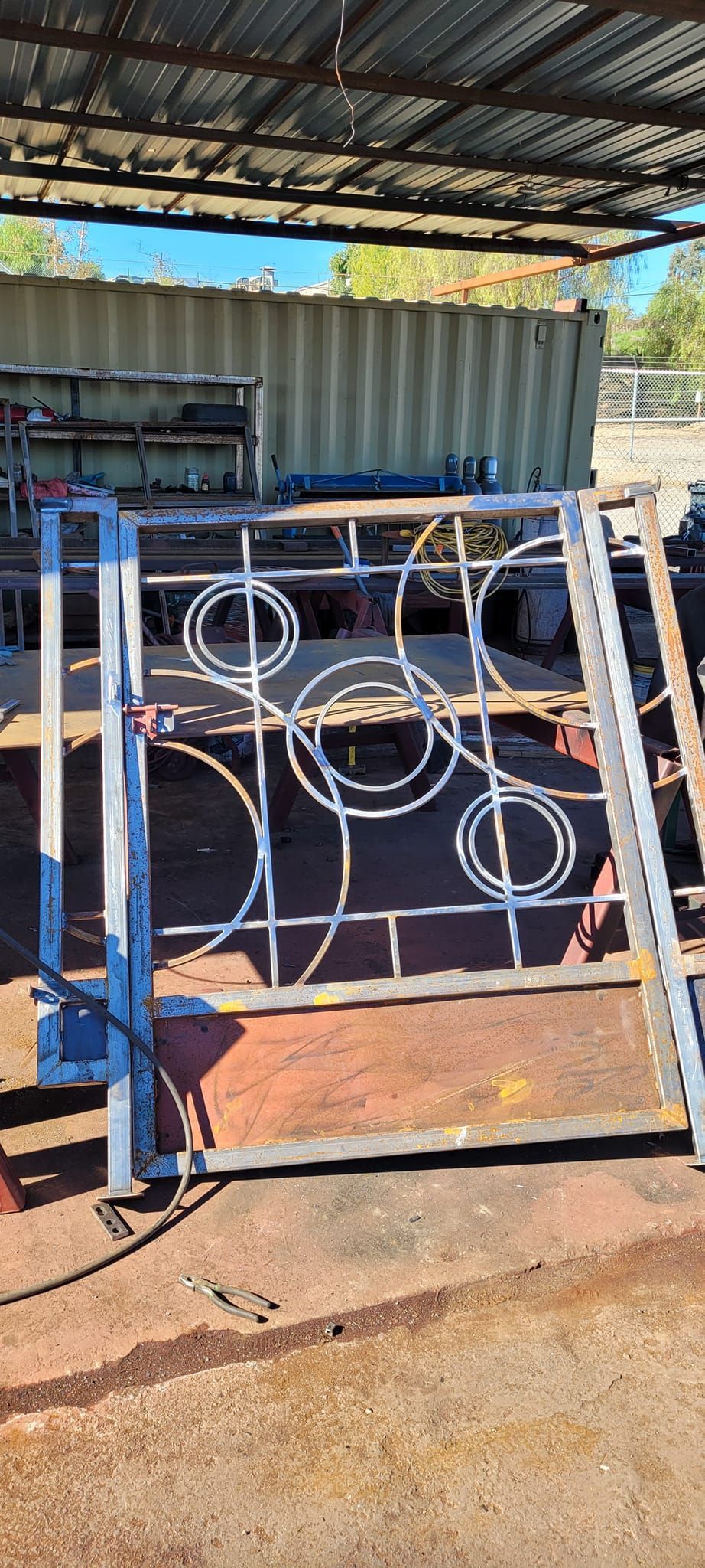 A metal gate with circles on it is sitting under a roof.
