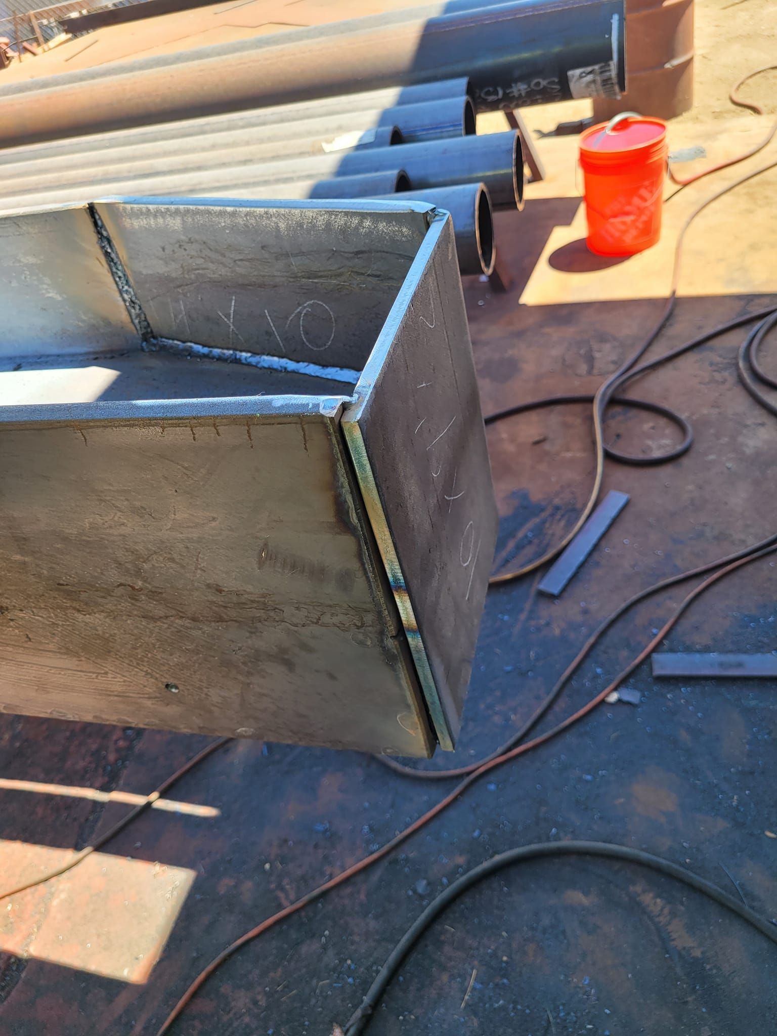 A piece of metal is sitting on a table next to a red bucket.