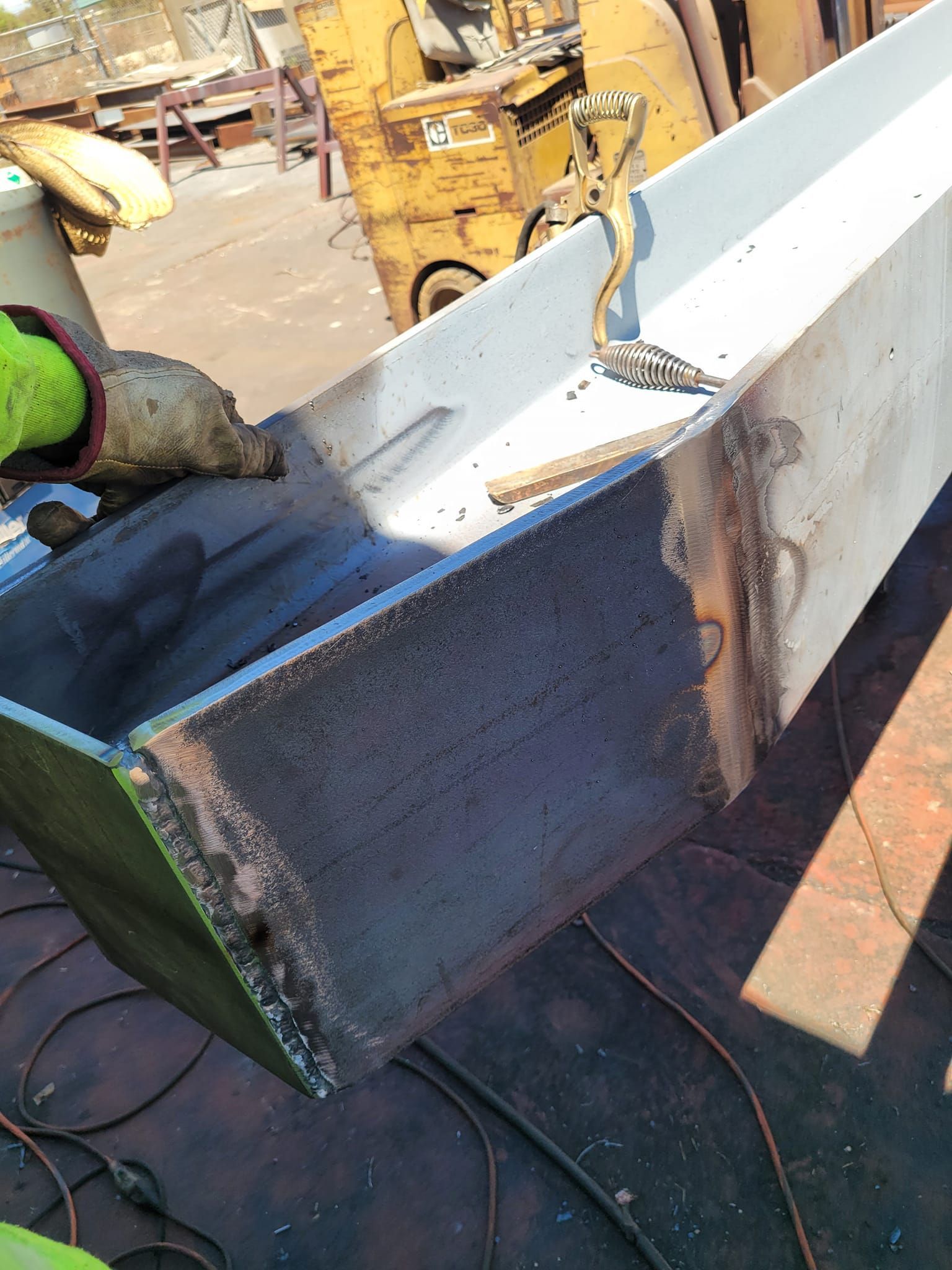 A person is welding a piece of metal in a factory.
