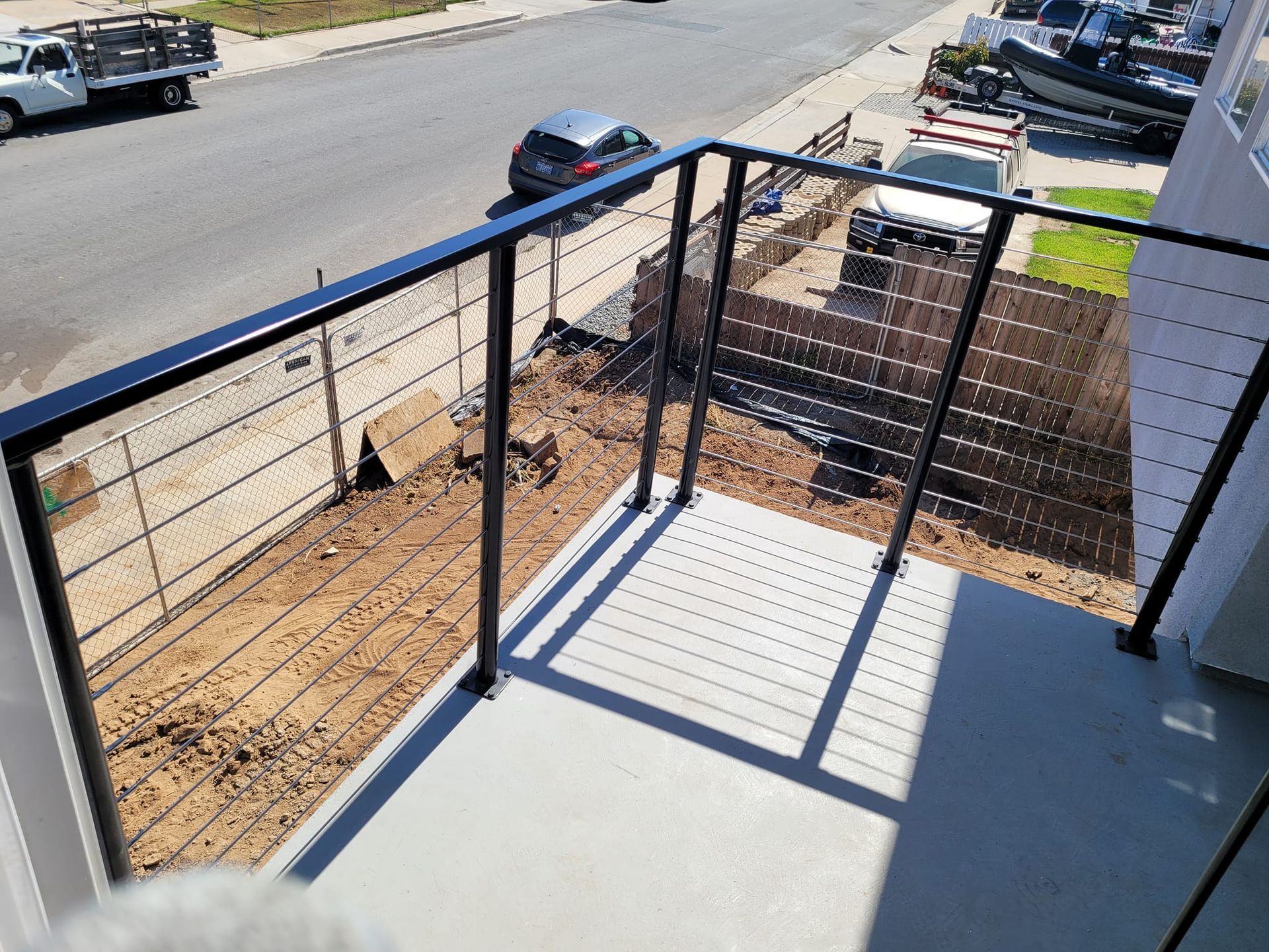A balcony with a black railing and a view of a street.