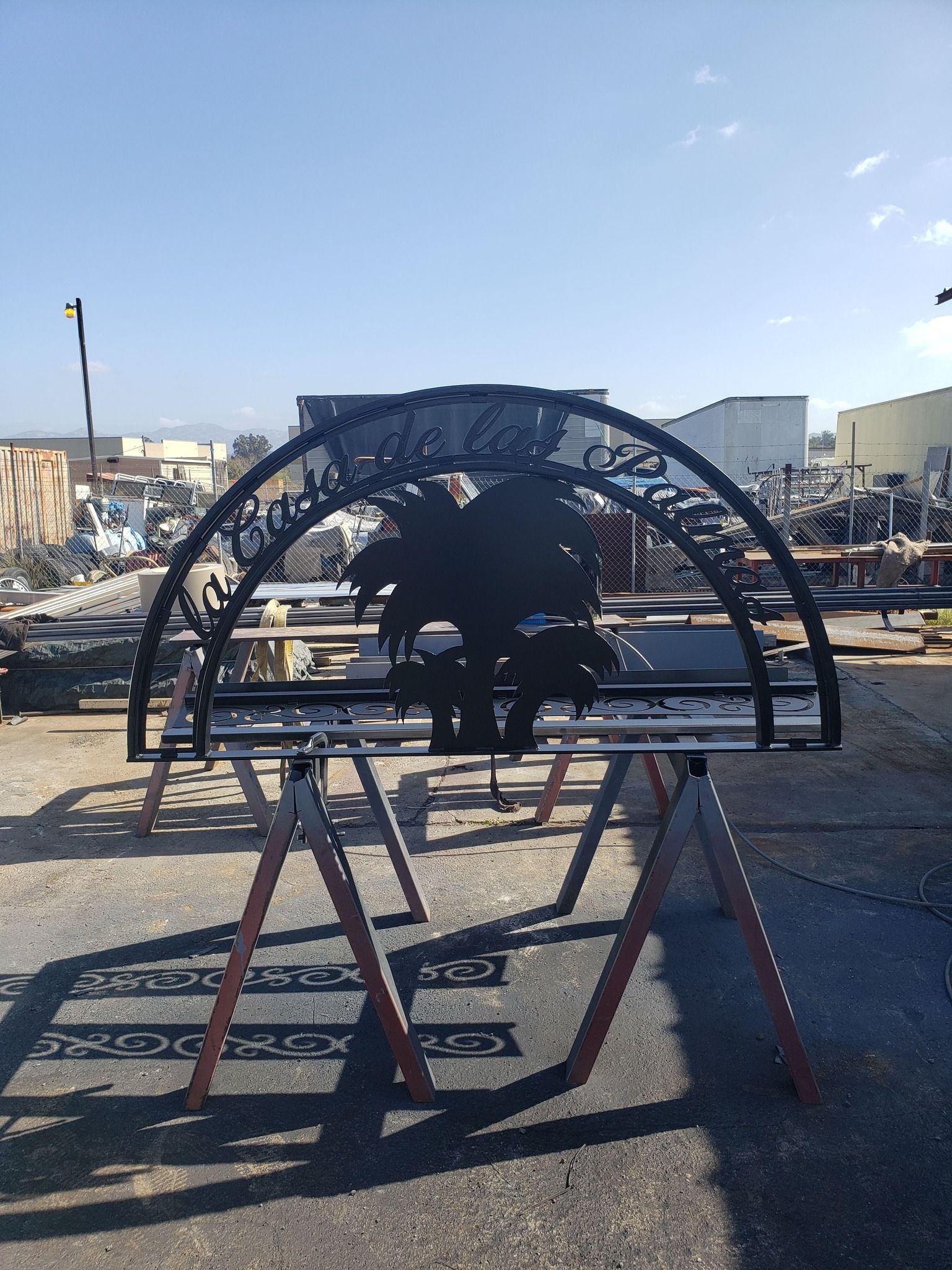 A metal sculpture is sitting on a wooden stand in a parking lot.